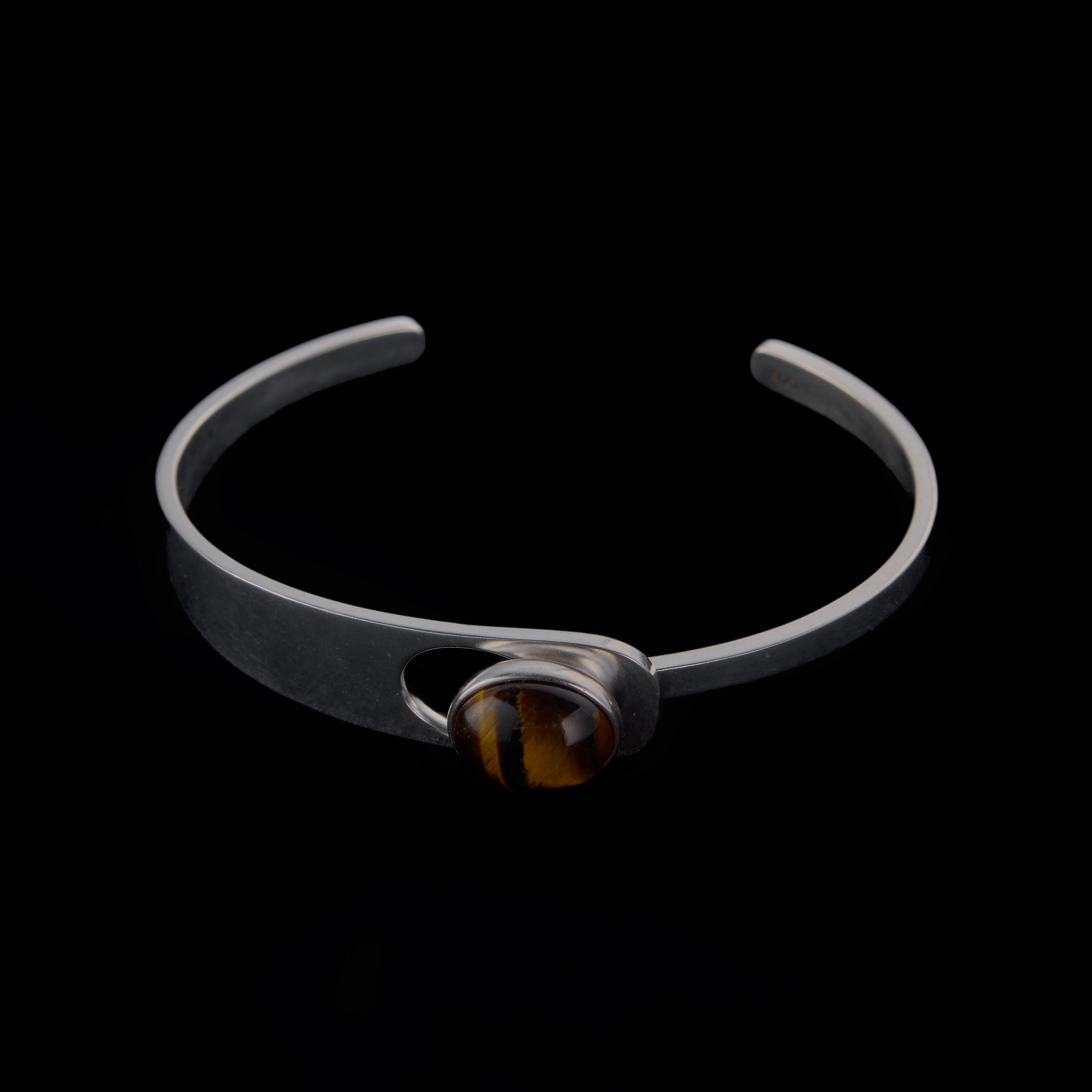 Saël Aperture Cuff in muted silver, 49*59mm interior diameter, with an elliptical cutout and bezel-set Tiger Eye