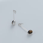 Minimalist vertical drop earrings in 925 sterling silver and natural Tiger Eye. Featuring a unique composite sphere and muted lustre finish. Architectural jewelry by Saël.